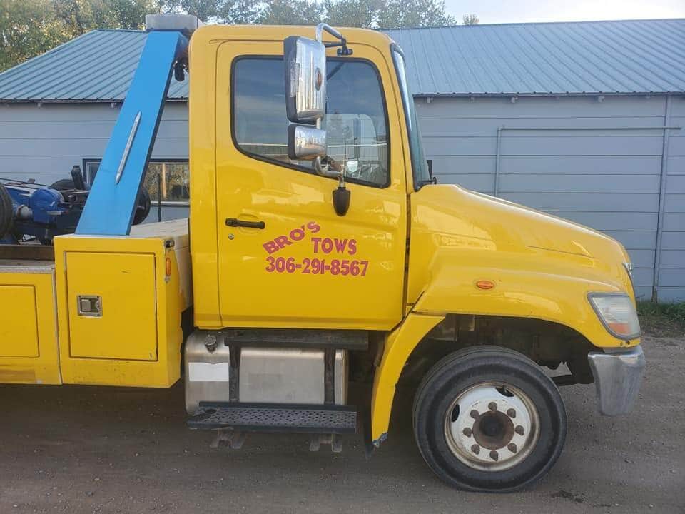 Bro's Tows yellow branded tow truck with phone number